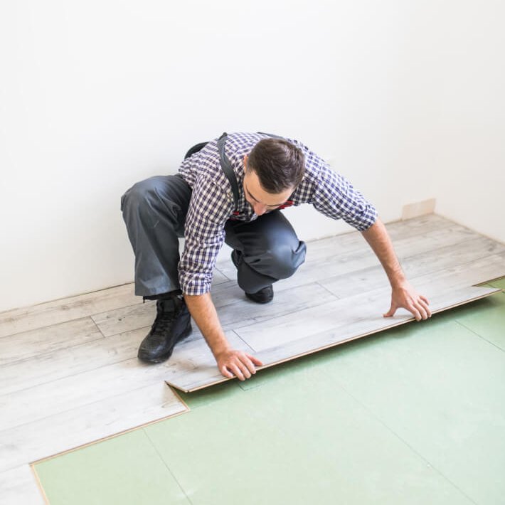 worker processing a floor with laminated flooring boards