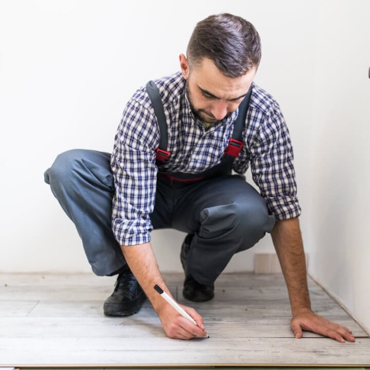 Young worker lining a floor with laminated flooring boards